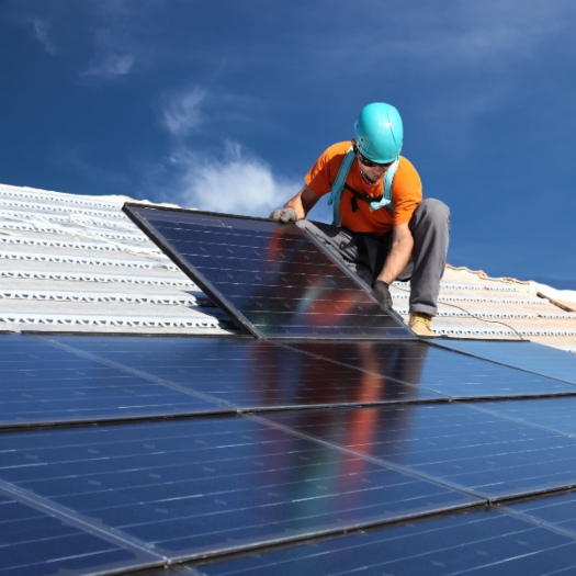 Solar installer installing solar panels on residential building